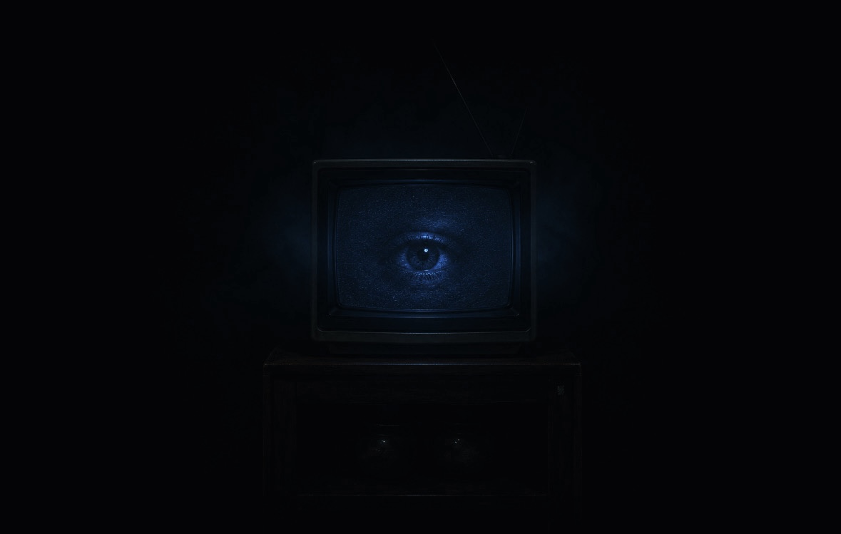 Televisão antiga isolada no escuro exibindo um olho azul — atmosfera de vigilância